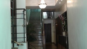 A hallway with a staircase, a chandelier, and a potted plant. - Hotel São Bento (Belo Horizonte)