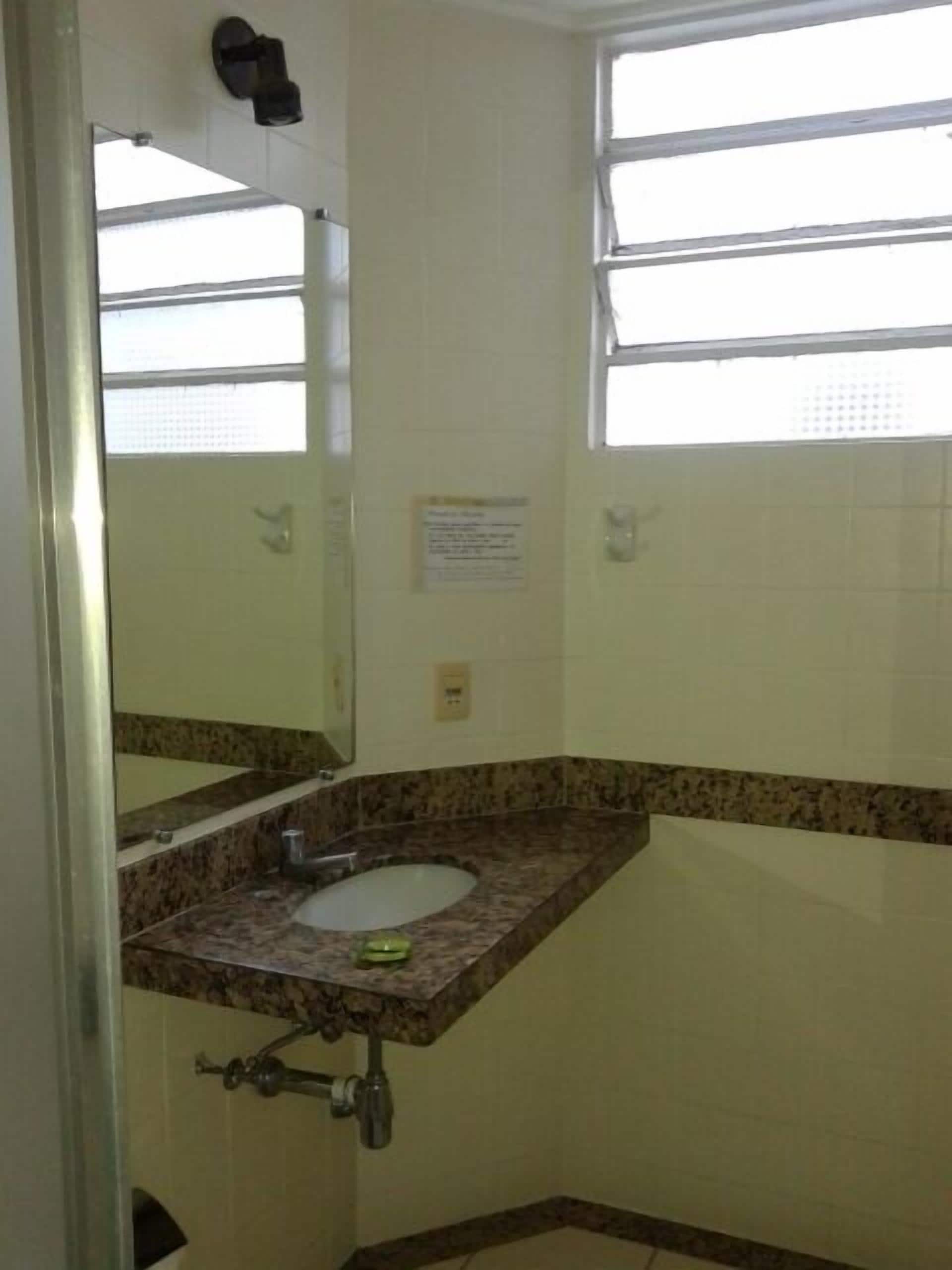 A bathroom with a marble sink, a mirror, and a window.