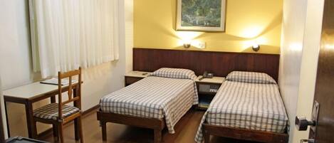A room with two beds, a desk, and a chair.