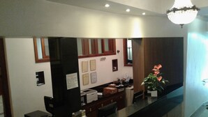 A reception desk with a black counter, a potted plant, and framed certificates on the wall. - Hotel São Bento (Belo Horizonte)
