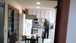 A kitchen with a dining area, a refrigerator, a microwave, and a person standing near the counter.