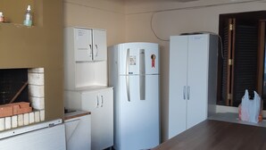 A compact kitchen with white cabinets, a white refrigerator, and a wooden countertop.
