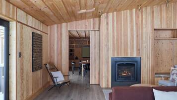 A wooden interior with a fireplace, a sofa, and a dining area.