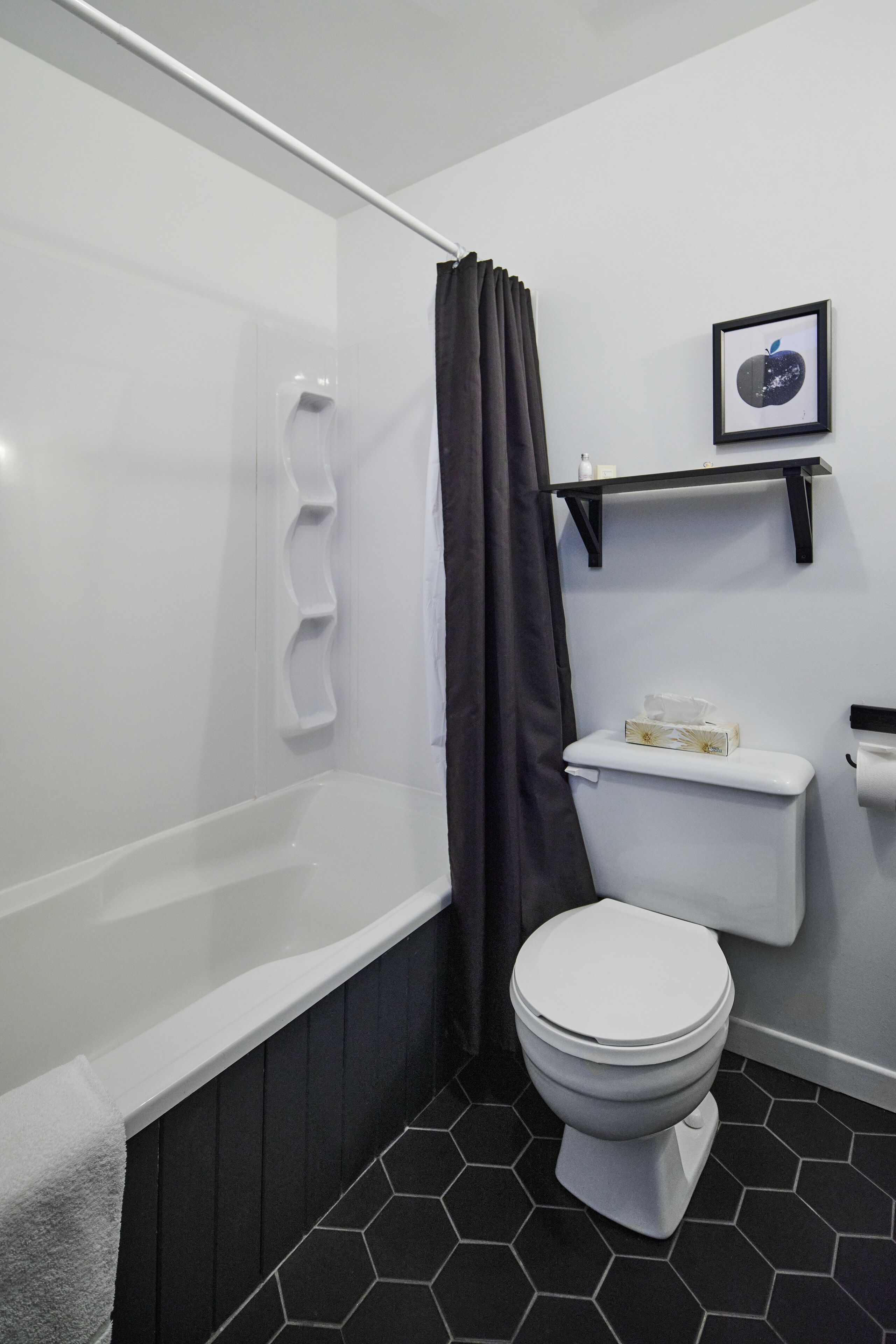 A modern bathroom with a white bathtub, a toilet, and a shower curtain.