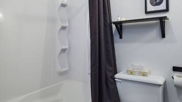 A modern bathroom with a white bathtub, a toilet, and a shower curtain.