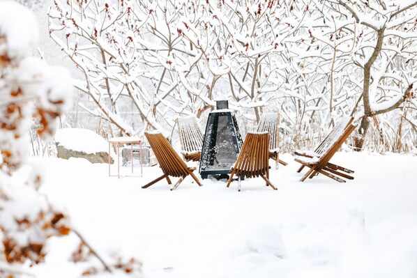 A snow-covered outdoor seating area with a metal table and wooden chairs. - Balnea Hotel (Bromont)
