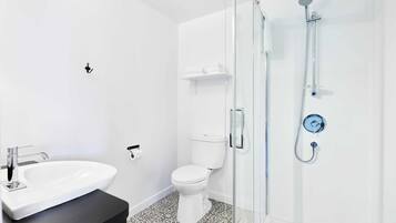 A modern bathroom with a white sink, toilet, and glass-enclosed shower.