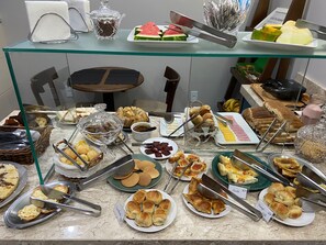 A buffet with various food items including bread, pastries, and fruits. - Pousada Canasvieiras (Florianópolis)