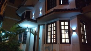 Una casa de varios pisos con un balcón, ventanas amplias y una entrada bien iluminada.