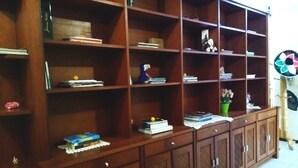 Un mueble de madera con varios estantes y cajones, que contiene libros, objetos decorativos y una pequeña planta.