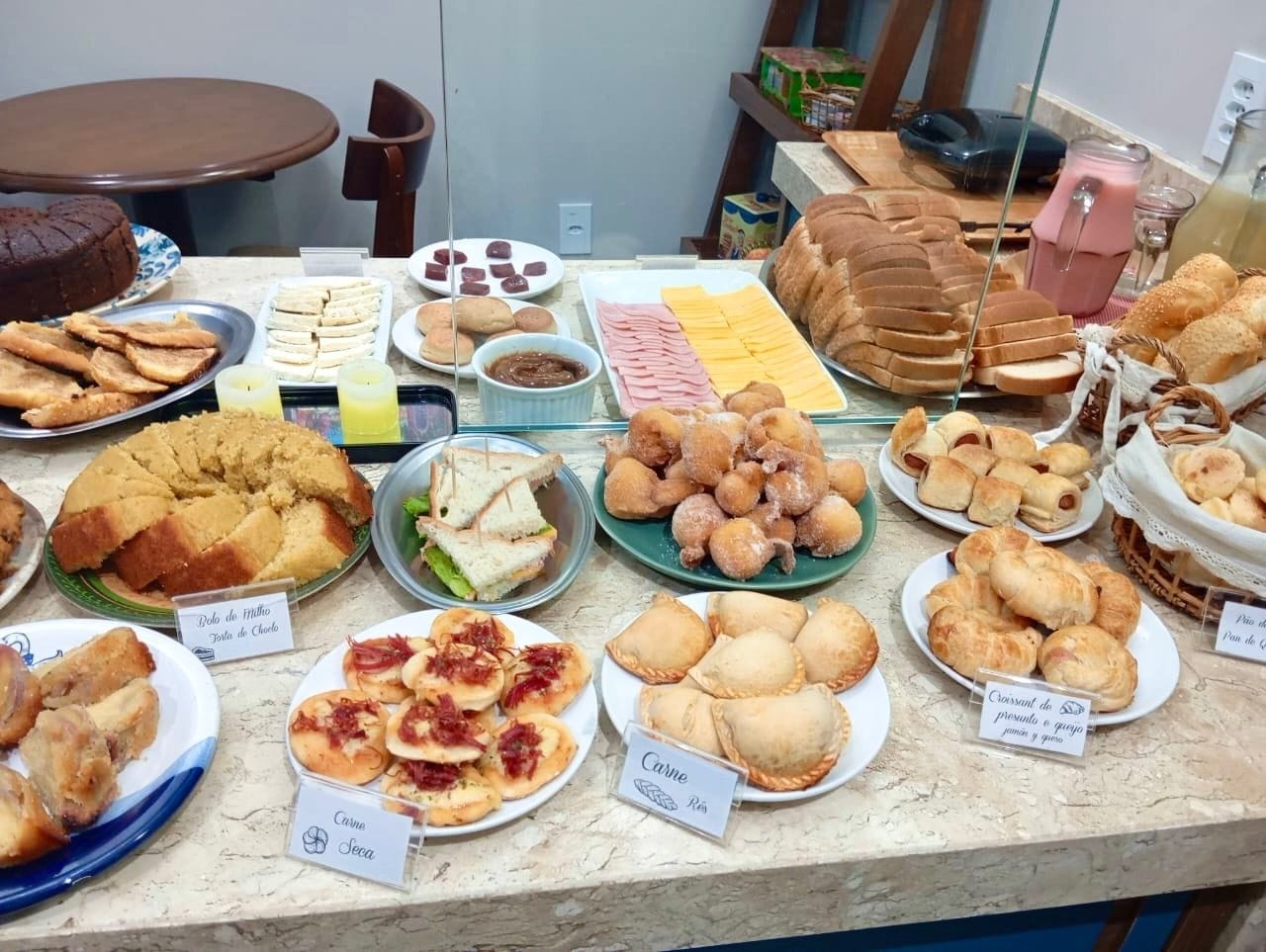 Un bufé con diversos alimentos, incluyendo pasteles, sándwiches y productos de repostería.