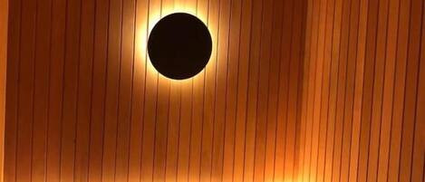 A room with vertical wooden paneling and a circular light fixture on the ceiling.