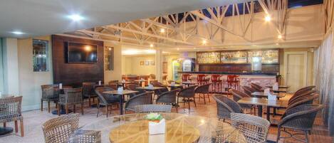 A spacious indoor dining area with wicker furniture, a bar, and a television screen.