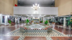 Un hall espacioso con una fuente central, un candelabro y un diseño de piso a cuadros.