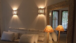 A bedroom with a bed, two bedside lamps, a telephone, and a mirror with a stone frame. - Pousada Náutilus (Ilhabela)