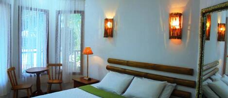 A hotel room with a bed, a table, two chairs, a lamp, and a mirror.
