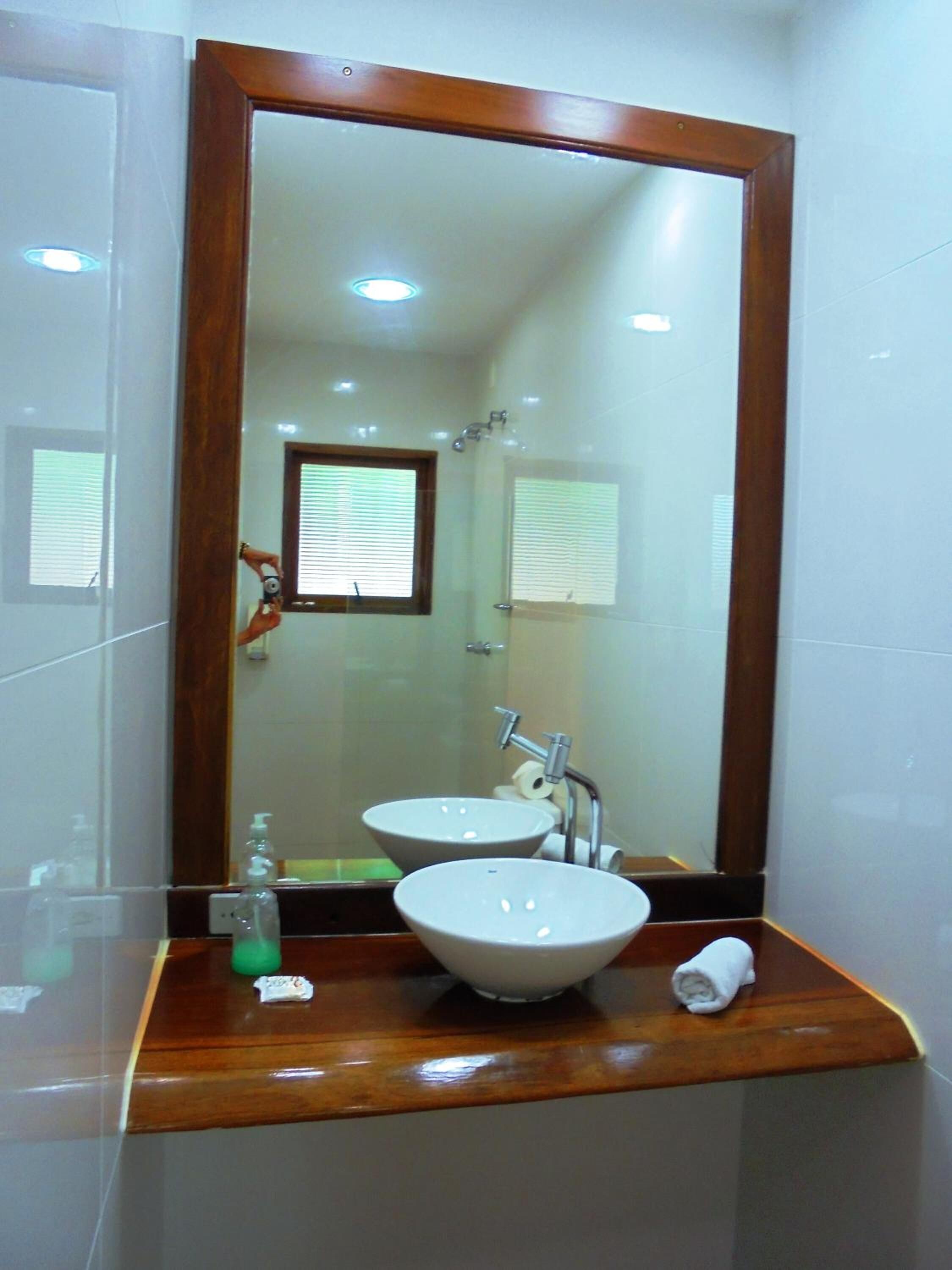 A bathroom with two sinks, a mirror, and a window with blinds.