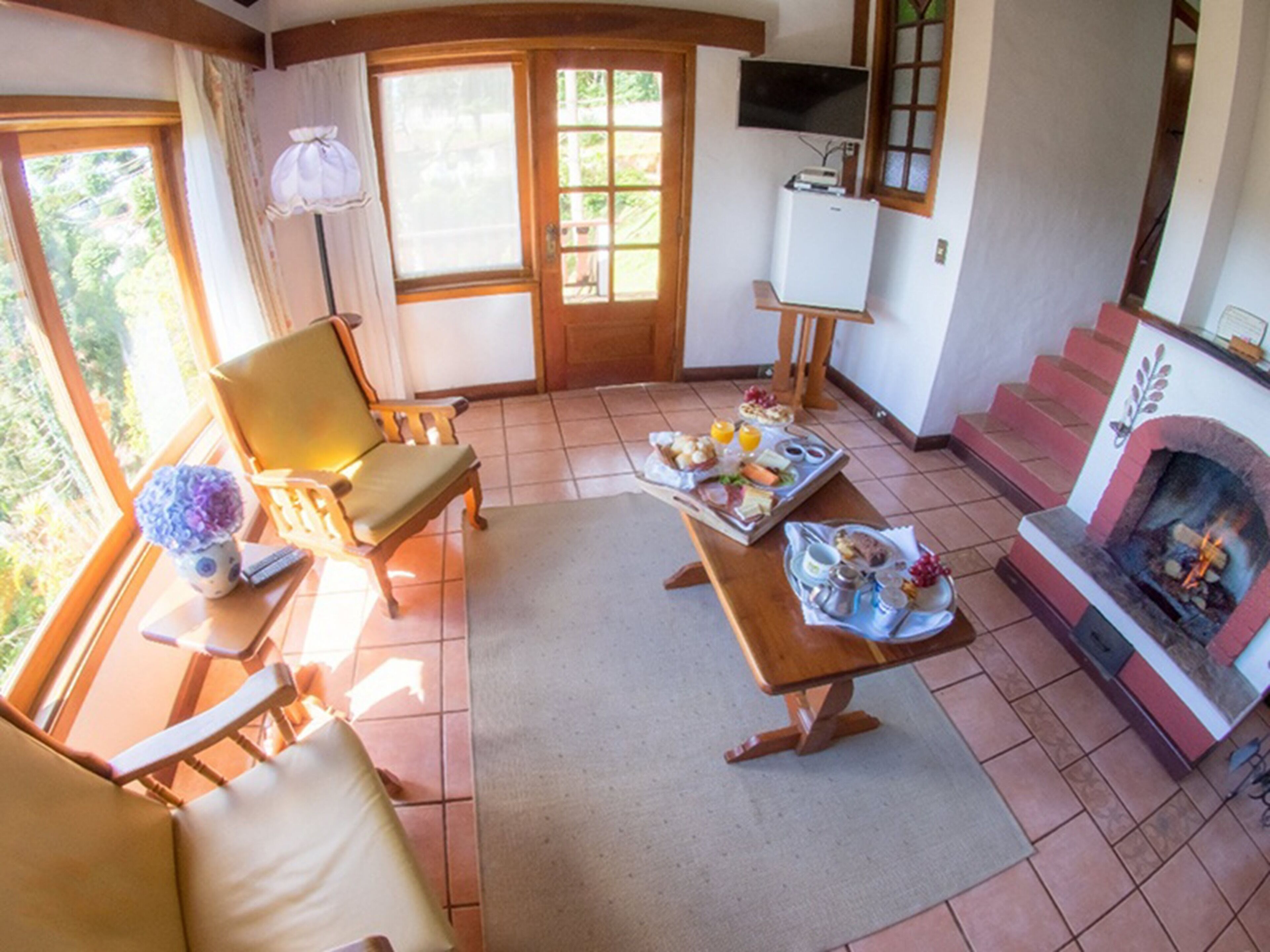 A cozy living room with a fireplace, a dining table set with breakfast, and a comfortable seating area.