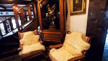 A staircase with wooden railings and a statue in the center. There are two chairs with fluffy white covers.