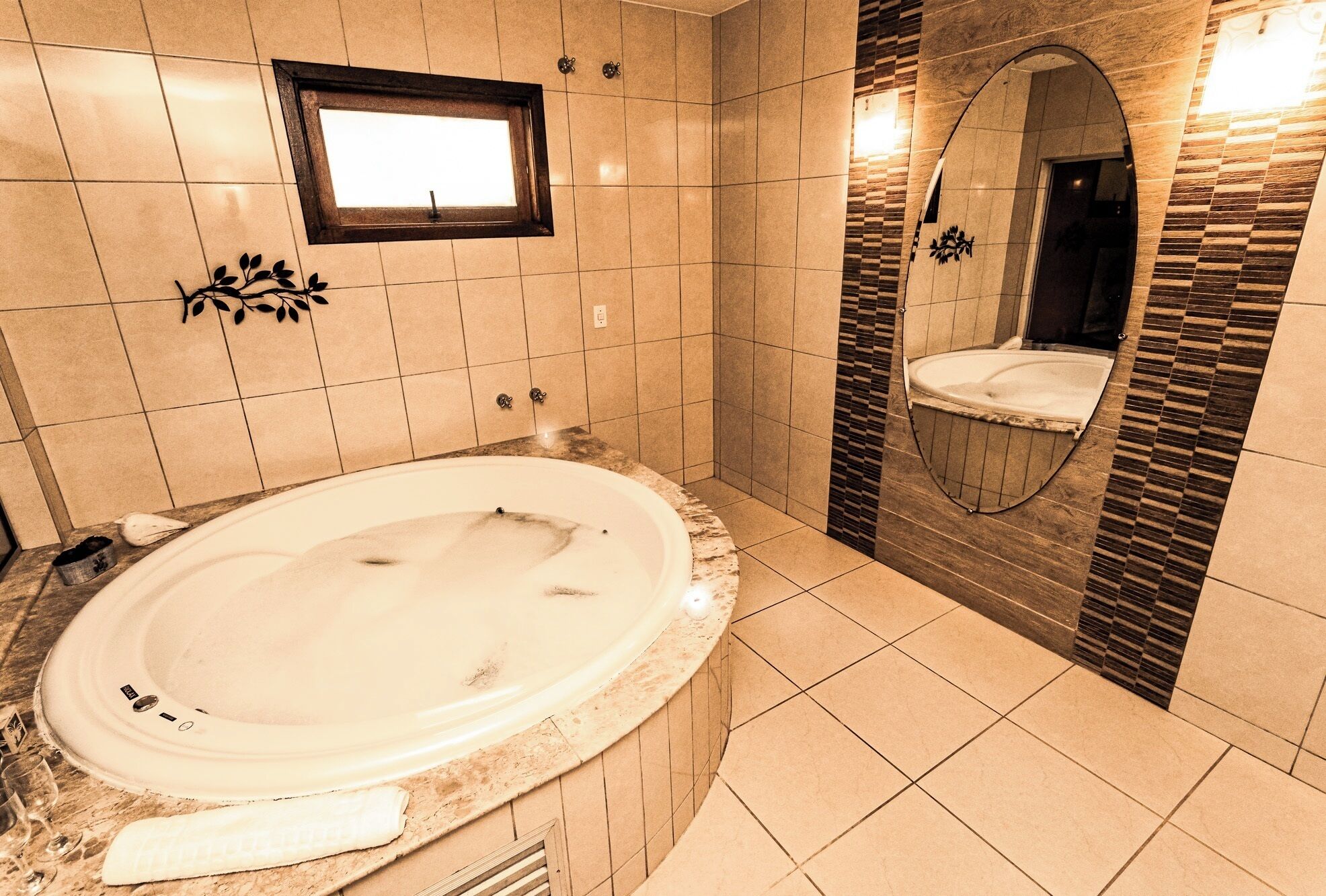 A modern bathroom with a large oval bathtub, a small window, and a decorative mirror.