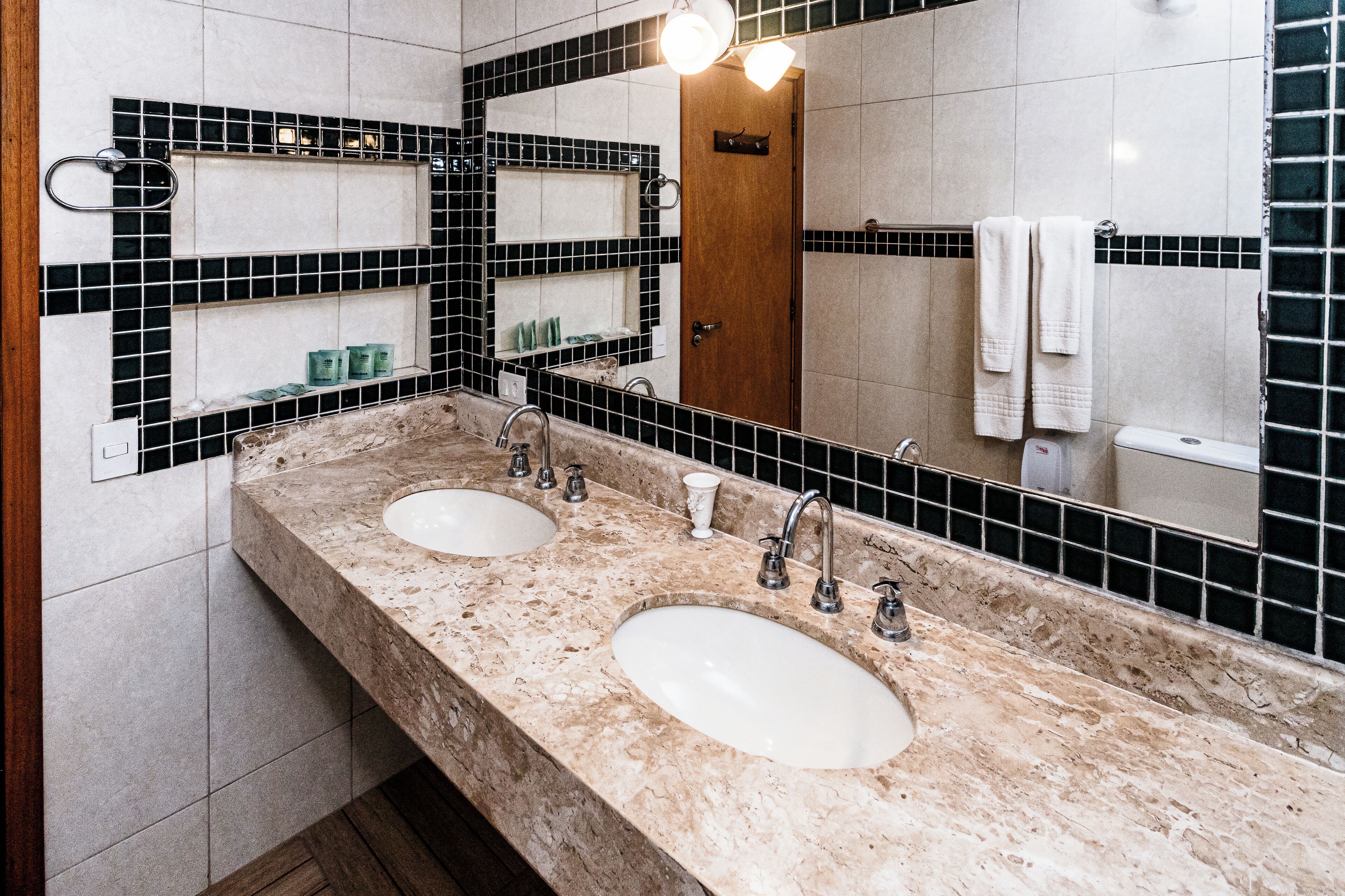 Ein Badezimmer mit zwei Waschbecken, einem Spiegel und einem Ablagefach mit Pflegeprodukten.