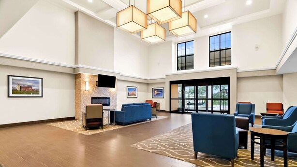 A spacious lobby with a fireplace, comfortable seating, and large windows providing natural light. - Comfort Suites Rensselaer near Fair Oaks (Rensselaer)