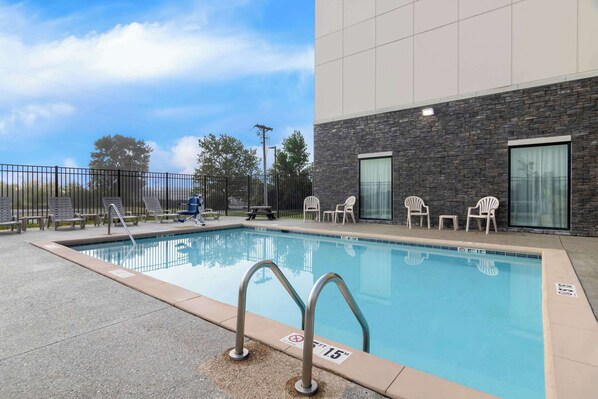 Una piscina con una pared de piedra y una barandilla de metal.