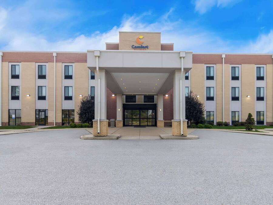 A Comfort Inn hotel entrance with a clear sky, a brick facade, and a central entrance flanked by two columns.