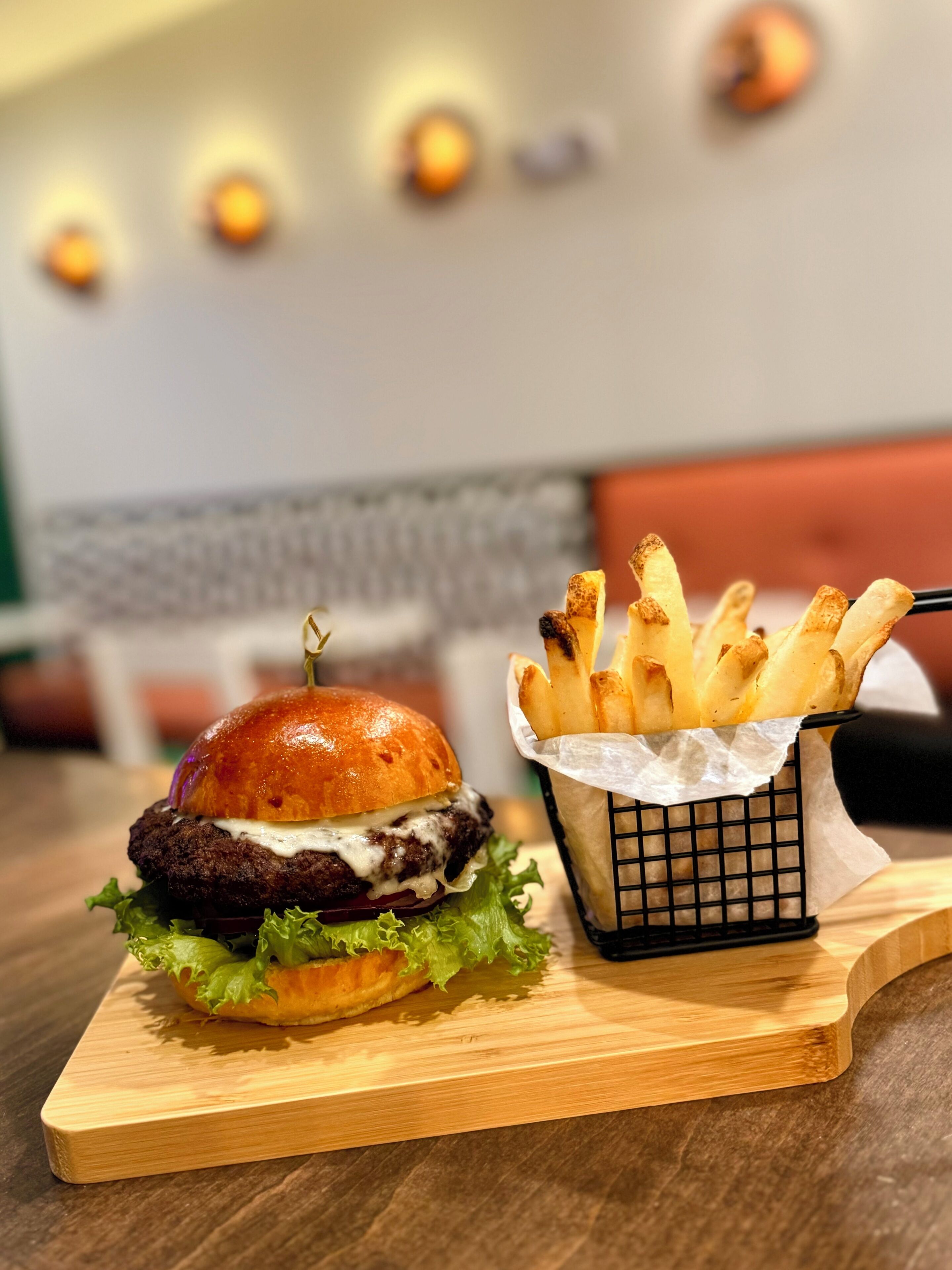 A burger and fries on a wooden board.