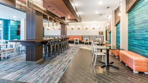 Een modern restaurant met een bar, zitplaatsen en een gestreept plafond.