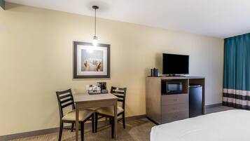 A hotel room with a bed, a desk with a chair, a television, a microwave, and a coffee maker.