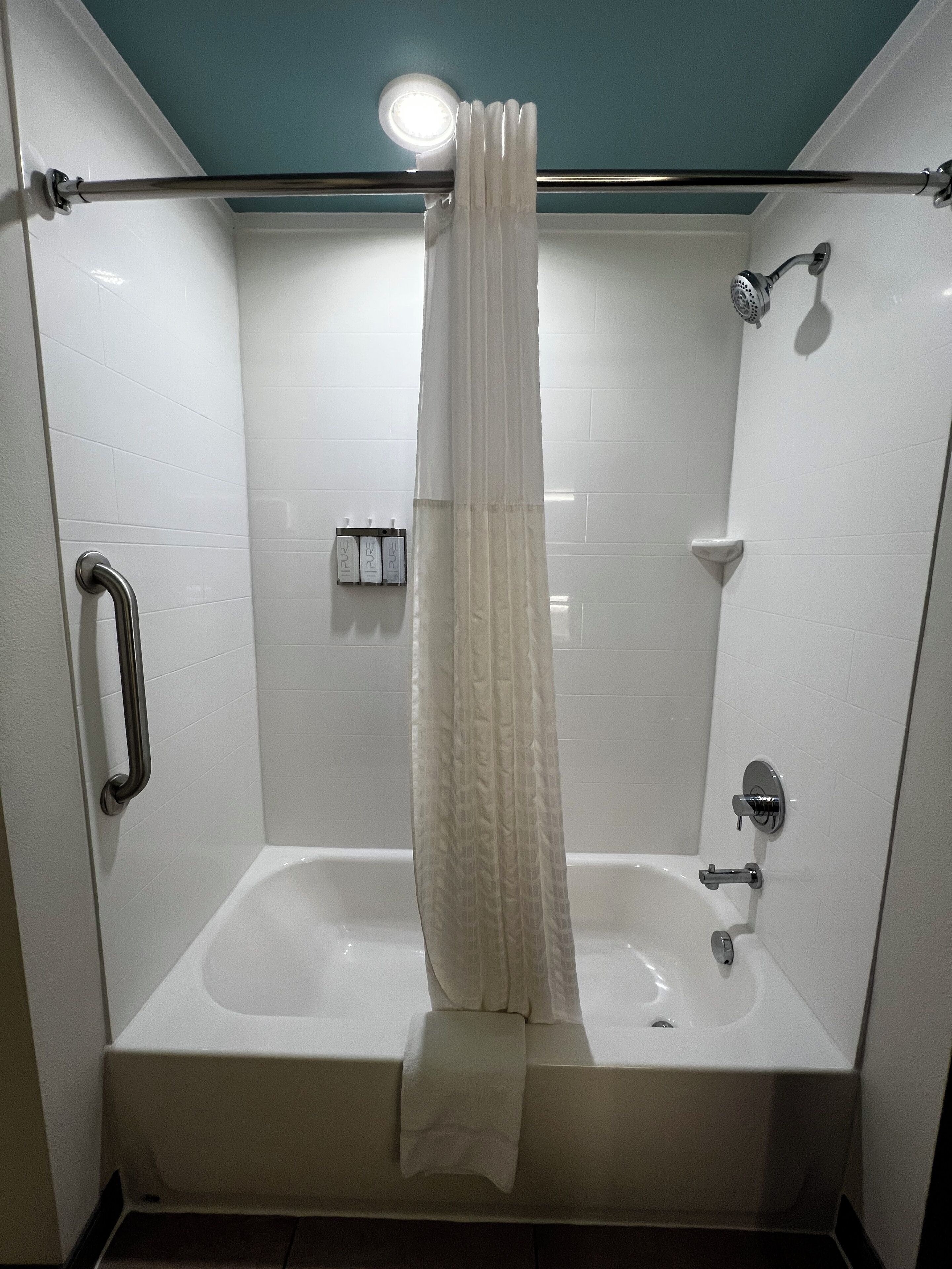 A modern bathroom with a bathtub, a shower, and a handrail.