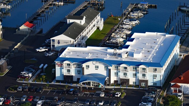 A large hotel with a blue roof, multiple parking lots, and a marina with boats.