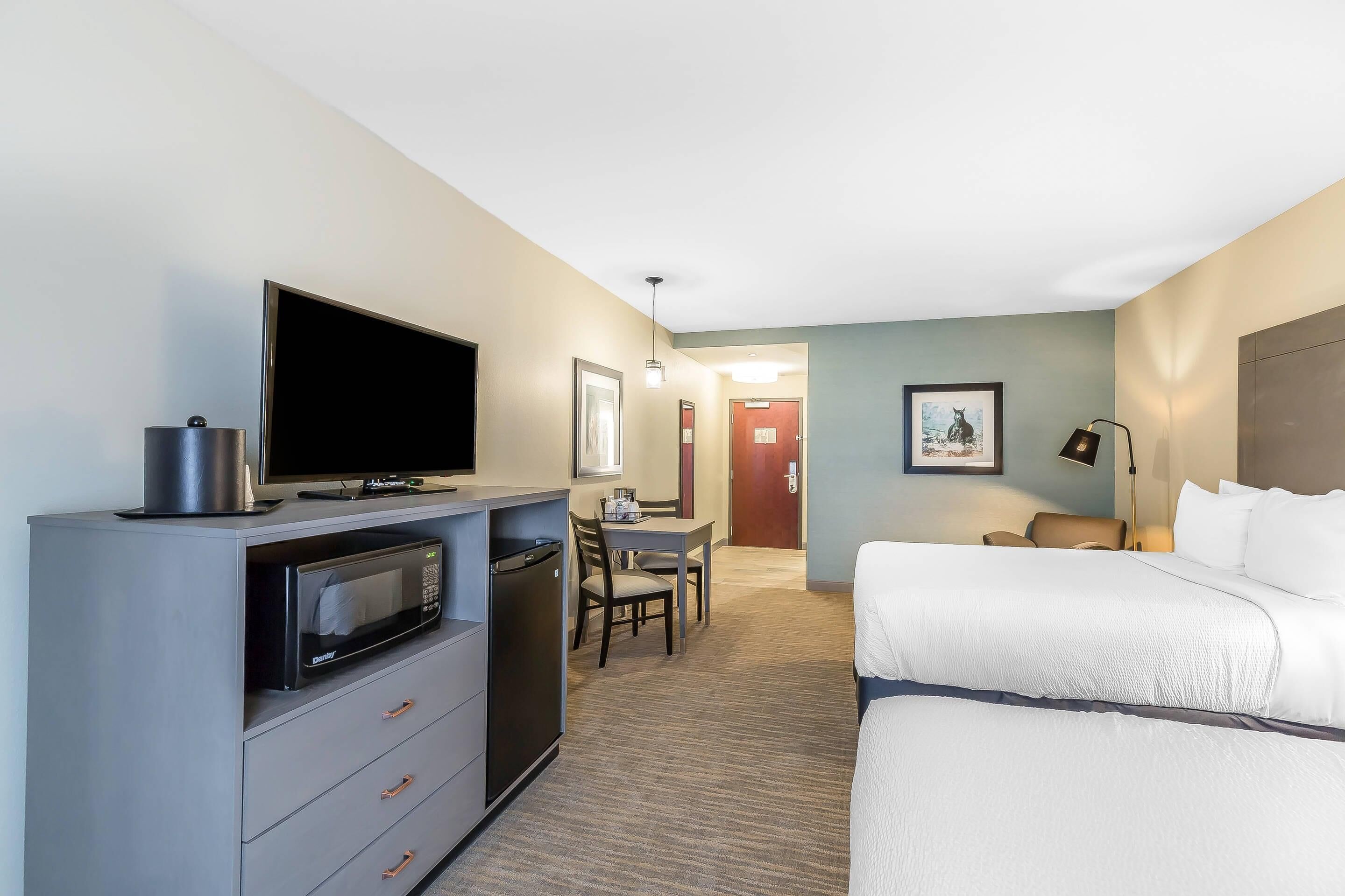 A hotel room with a bed, a desk with a chair, a microwave, and a television.