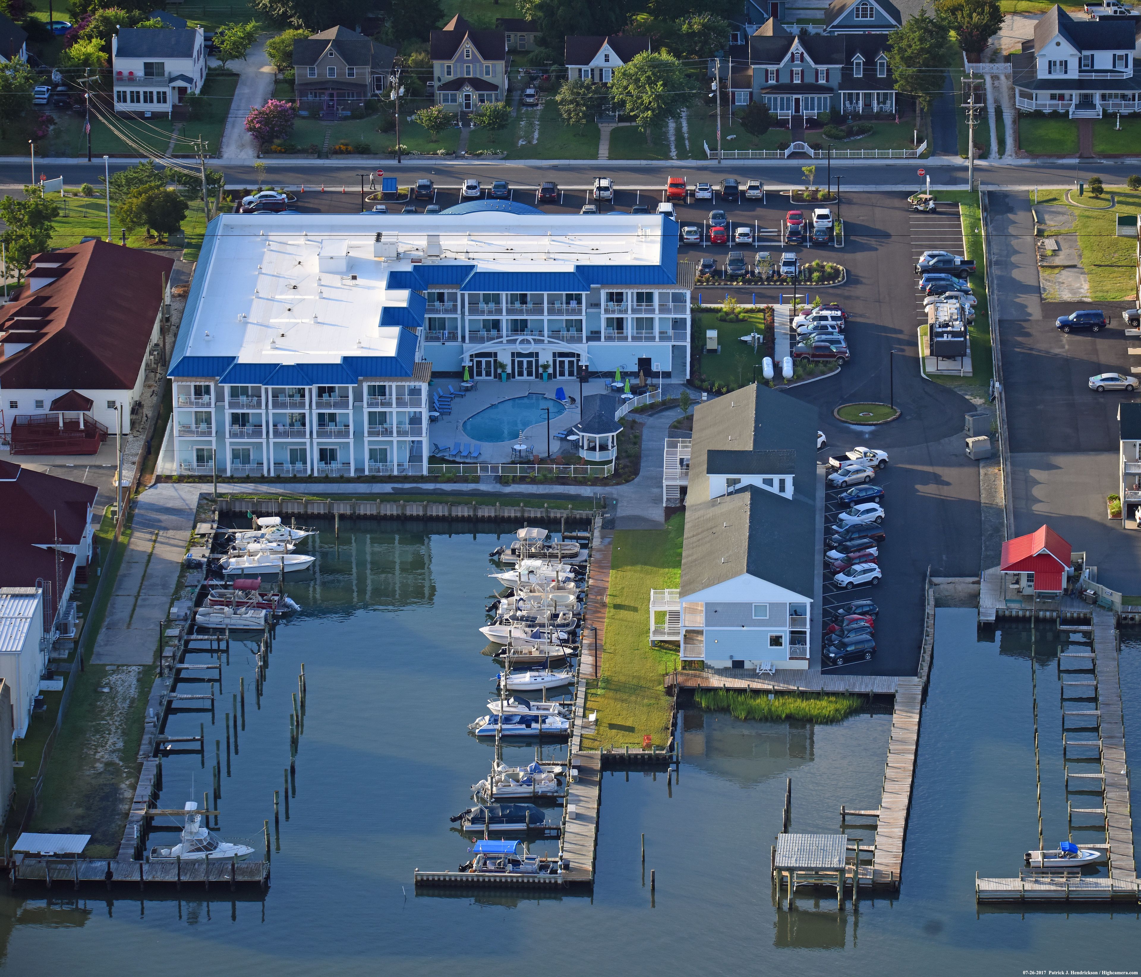 A marina with boats docked, a building with a blue roof, and a parking lot.