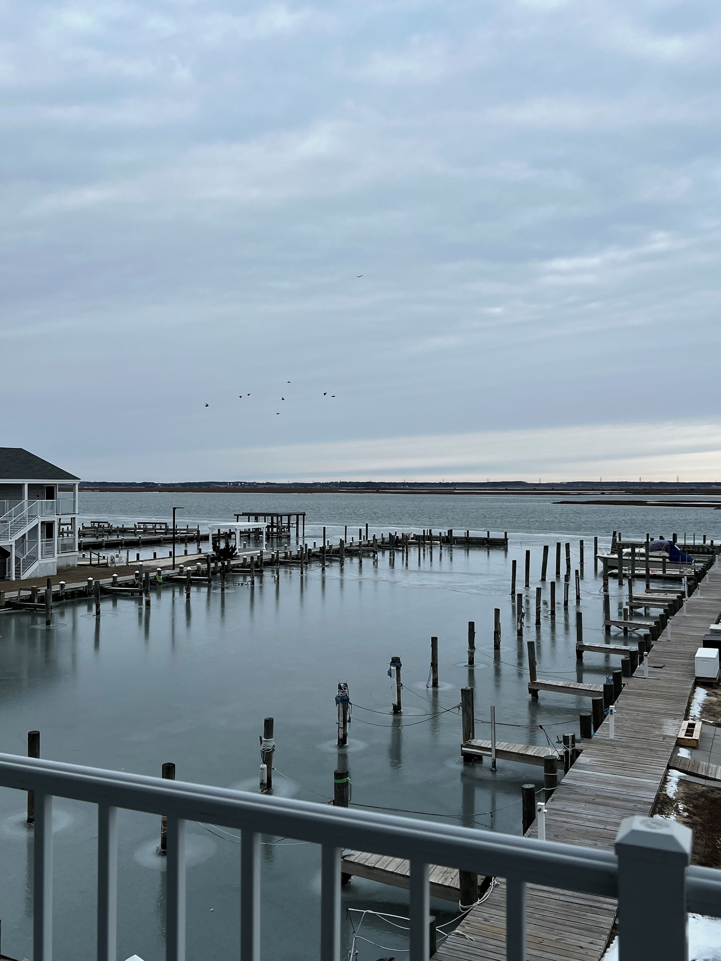 A waterfront pier with a wooden walkway and a building with a balcony.