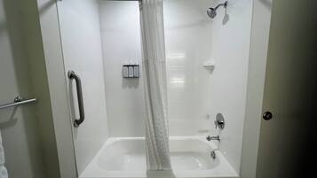Una ducha a nivel con bañera, un barandal, un cabezal de ducha y un panel de control.