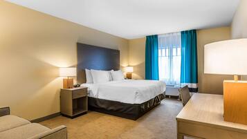 A hotel room with a bed, bedside tables, a desk, and a chair.