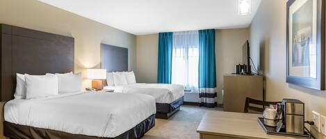 A hotel room with two beds, a desk, a chair, a lamp, a TV, and a window with curtains.