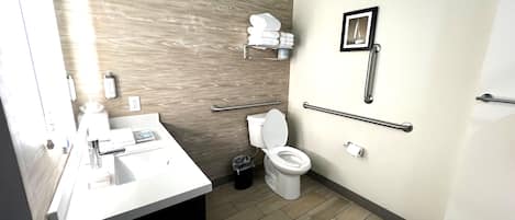 Un baño moderno con lavamanos, inodoro y barras de apoyo.