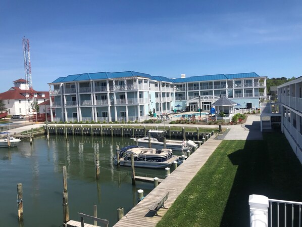 A waterfront hotel with multiple balconies, a dock with boats, and a clear sky.