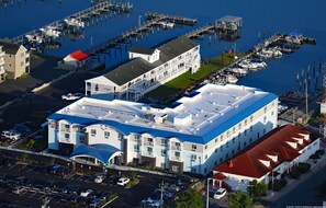 A multi-story hotel with a blue roof, located near a marina with boats docked. - Marina Bay Hotel & Suites, an Ascend Collection Hotel (Chincoteague)