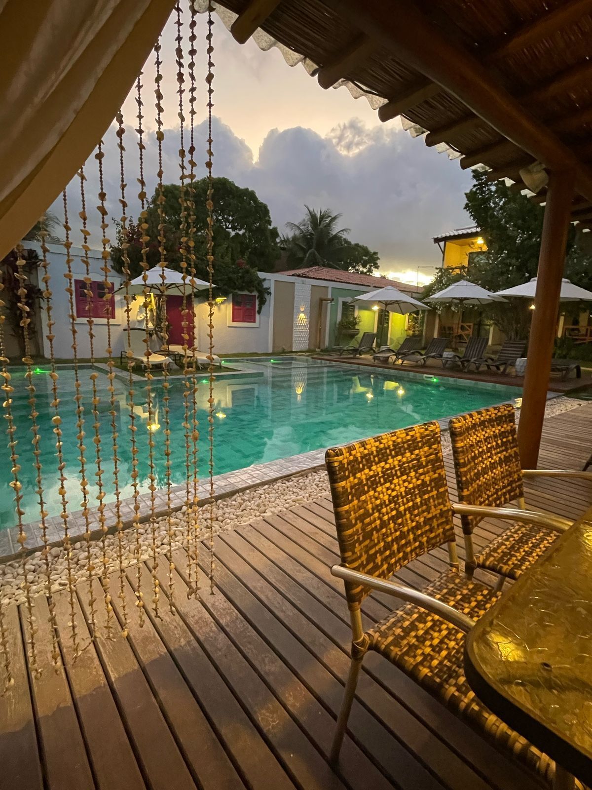 Une terrasse en bois avec une piscine, des chaises longues et un élément décoratif suspendu.
