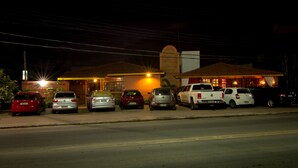 A row of parked cars in front of a building with a single-story structure and a sloped roof. - Pousada Le Baron (Marechal Deodoro)
