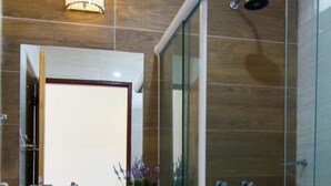 A modern bathroom with a glass shower enclosure, a white sink with a marble countertop, and a mirror above the sink. - Pousada Le Baron (Marechal Deodoro)