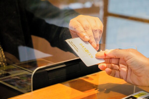 A hand holding a card with "DANIEL'S" written on it, being inserted into a card reader.
