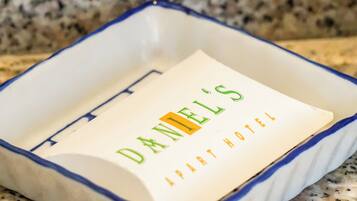 A white and blue ceramic tray with a card that reads "DANIEL'S APART HOTEL" on a granite countertop.