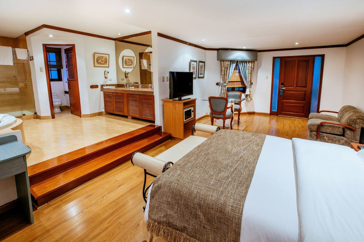 A hotel room with a bed, a TV, a desk, and a bathroom.