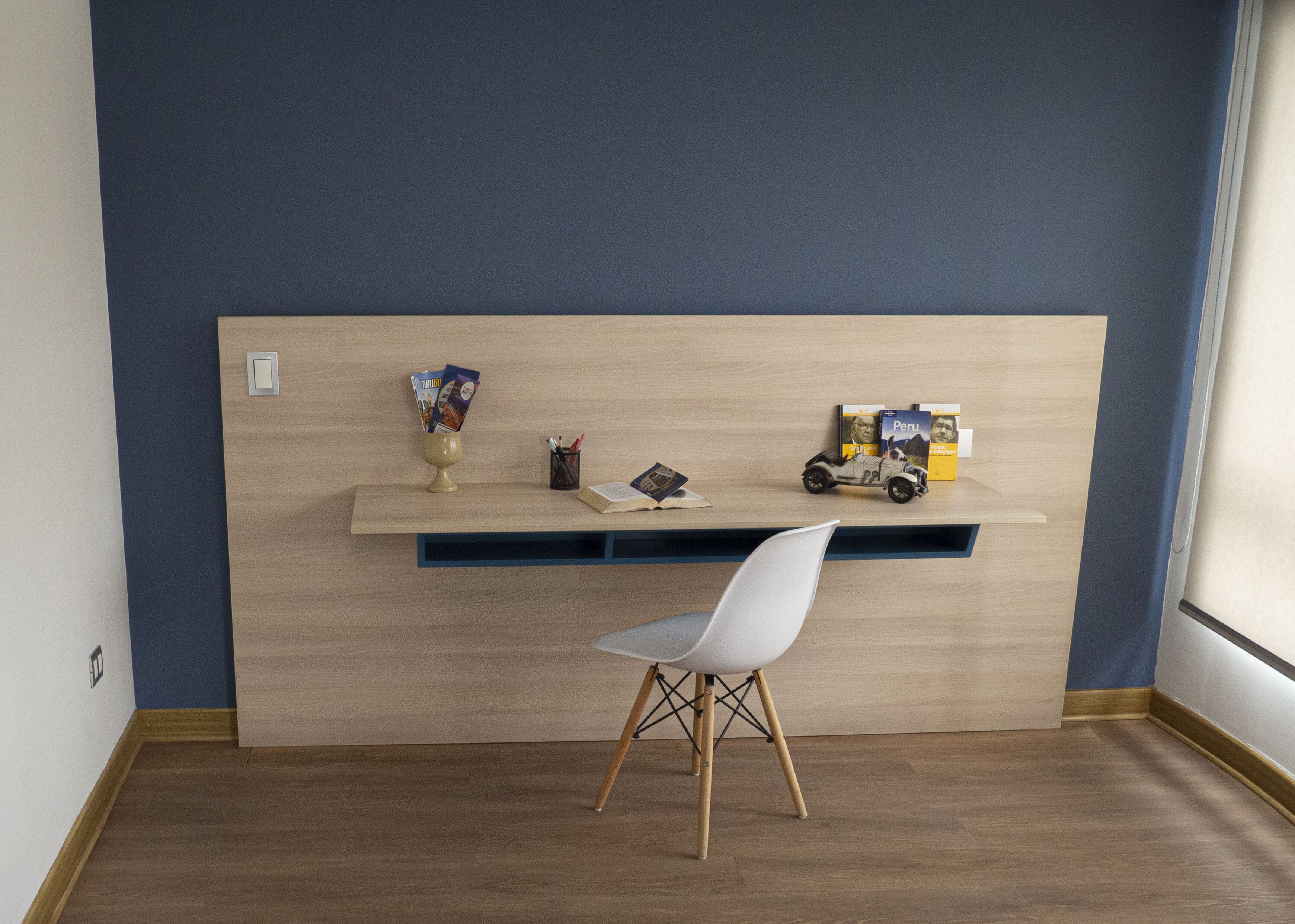 Une pièce avec un bureau en bois, une chaise blanche et une bibliothèque.