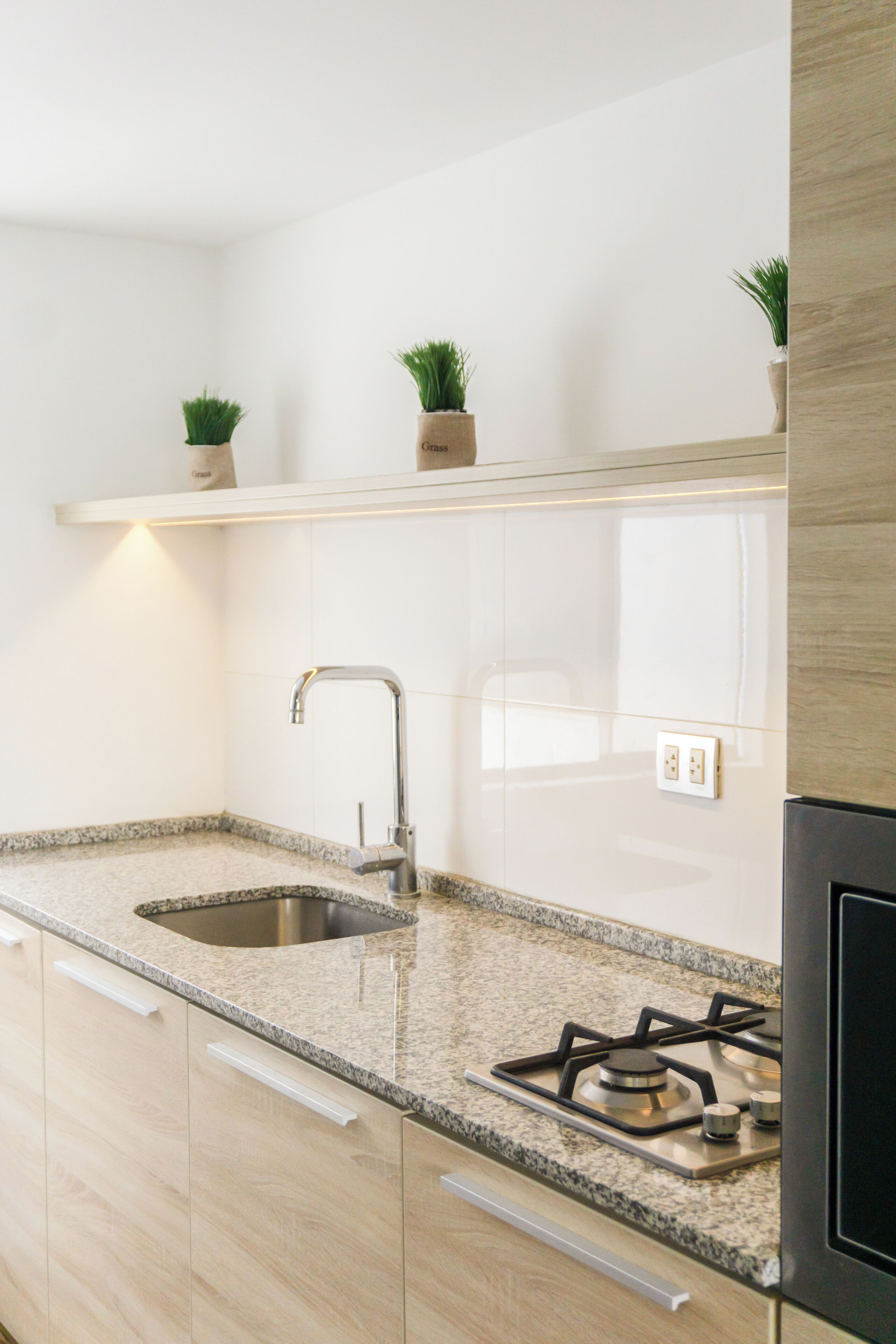 Une cuisine moderne dotée de plans de travail en granit, d’un évier en acier inoxydable et d’une cuisinière à gaz.
